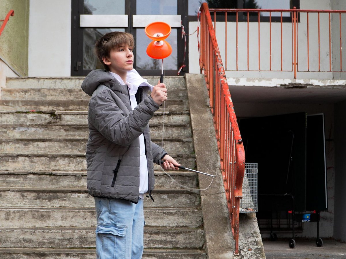 Ein Junge spielt vor einer Treppe mit einem Diabolo.