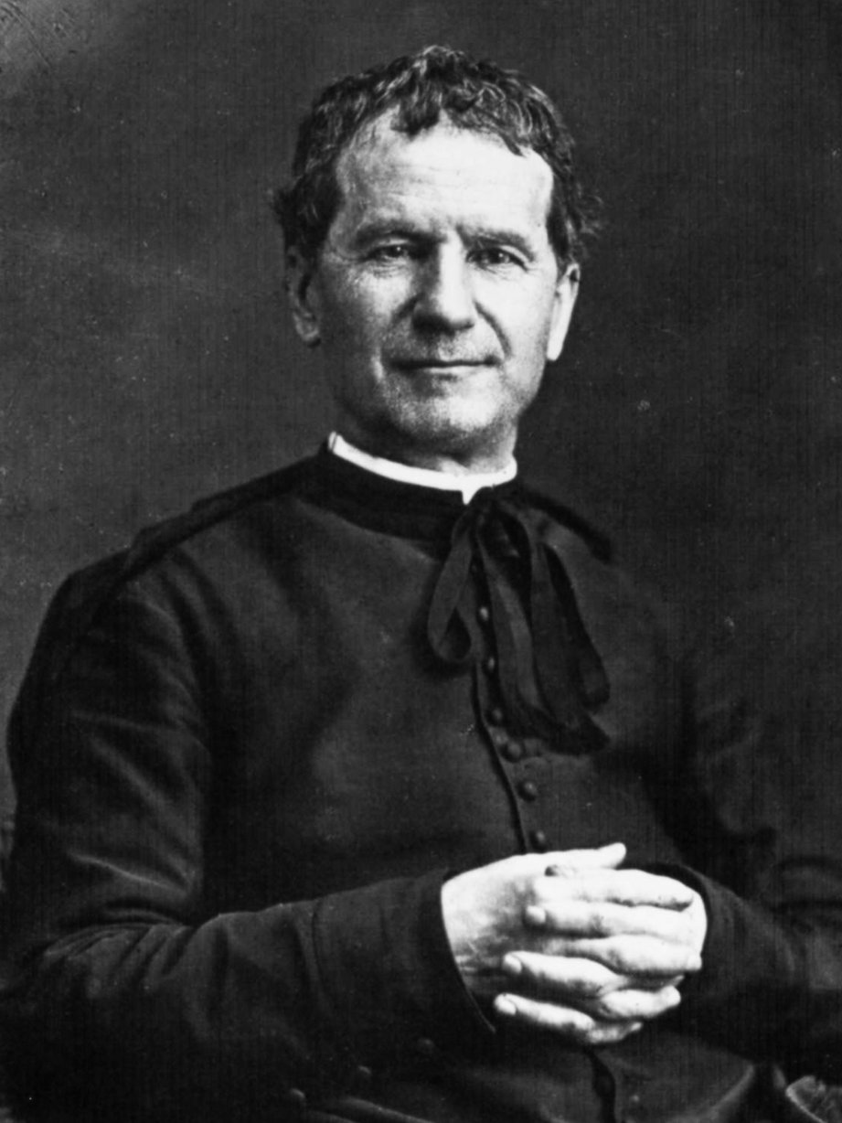 Schwarz-Weiß-Porträt des Heiligen Don Bosco, eines Priesters und Pädagogen, sitzend mit gefalteten Händen.