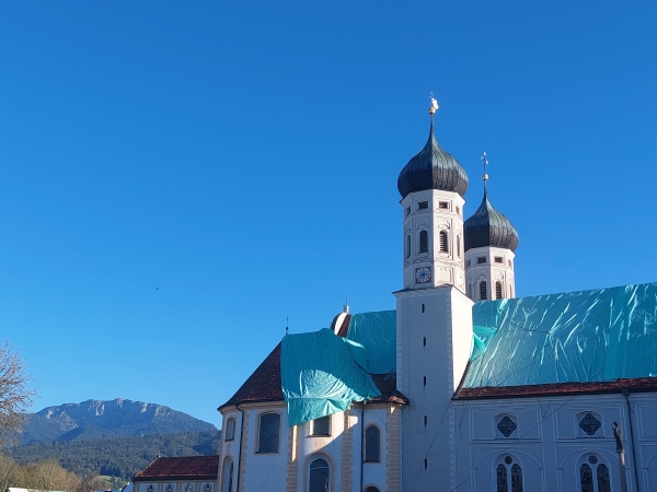 Die Basilika des Klosters Benediktbeuern fast komplett abgedeckt durch eine türkisfarbene Plane auf dem Dach