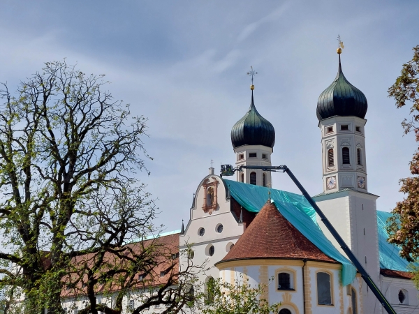 Ein Kran bringt eine Plane auf dem Dach der Basilika des Klosters Benediktbeuern nach dem Unwetter am 26. August 2023 an.